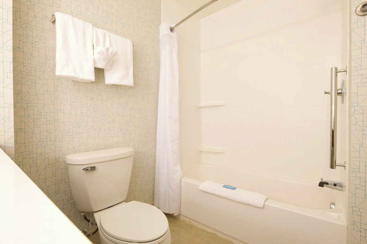 A bathroom with a toilet, a bathtub, and a shower curtain.