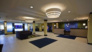 A spacious lobby with a reception desk, sofas, and a large television screen. - Holiday Inn Express & Suites Monroe by IHG (Monroe)