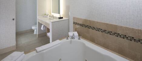A modern bathroom with a large bathtub, a sink, and a toilet.