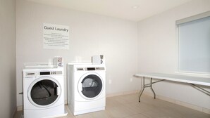 A guest laundry area with two washing machines and a table. - Holiday Inn Express & Suites Monroe by IHG (Monroe)