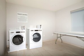 A guest laundry area with two washing machines and a table. - Holiday Inn Express & Suites Monroe by IHG (Monroe)
