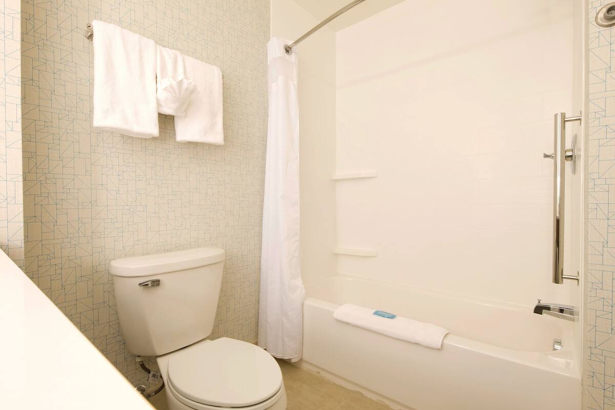Un baño con inodoro, bañera y cortina de ducha.