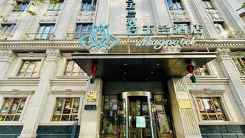 A grand hotel entrance with a prominent sign, a revolving door, and a large glass entrance.