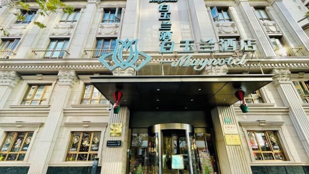 L’entrée d’un hôtel, avec une façade imposante, une porte tournante et une enseigne portant le nom de l’hôtel.