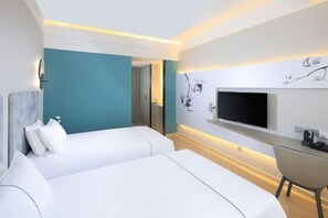 Une chambre d’hôtel moderne équipée d’un lit, d’un bureau et d’un téléviseur fixé au mur.