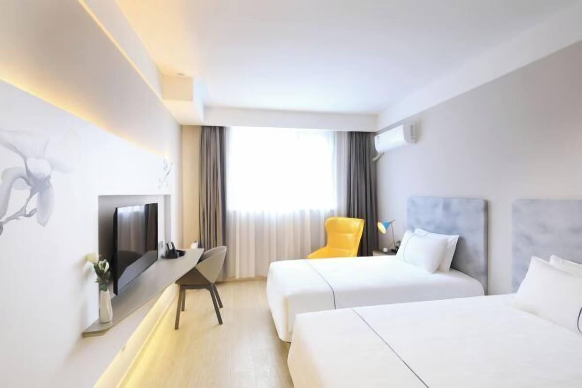 A hotel room with two beds, a TV, a desk, and a chair.