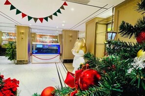 Hotellin aula, jossa on joulukoristeita, vastaanottotiski ja suuri ikkuna.