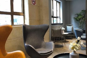Un intérieur moderne avec un espace salon comprenant un mélange de fauteuils et une table agrémentée d’un vase de fleurs.