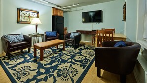 A living room with a sofa, chairs, a coffee table, a TV, and a patterned rug. - Atlantic Sands (Hampton)
