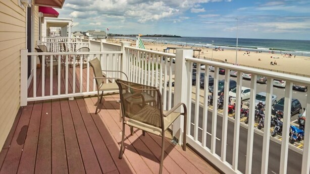 A wooden deck with a railing overlooking a beach. - Atlantic Sands (Hampton)