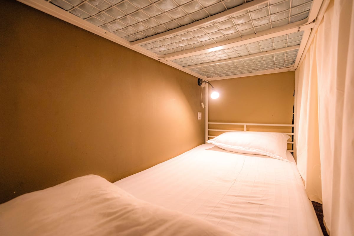 A single bed with white bedding in a room with beige walls and a white ceiling.