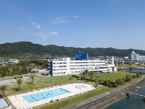 A resort with a swimming pool, a large building with a sign, and a mountainous backdrop.