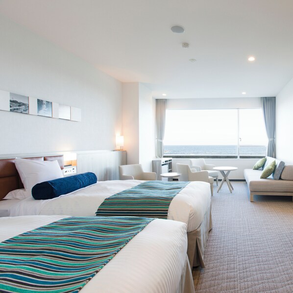 A hotel room with two beds, a sofa, a small table, and a view of the sea. - Shirahama Ocean Resort (Minamiboso)