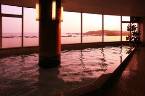 A large indoor pool with a view of the ocean through large windows. - Shirahama Ocean Resort (Minamiboso)