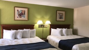 Habitación de hotel con dos camas, paredes verdes y cuadros enmarcados.