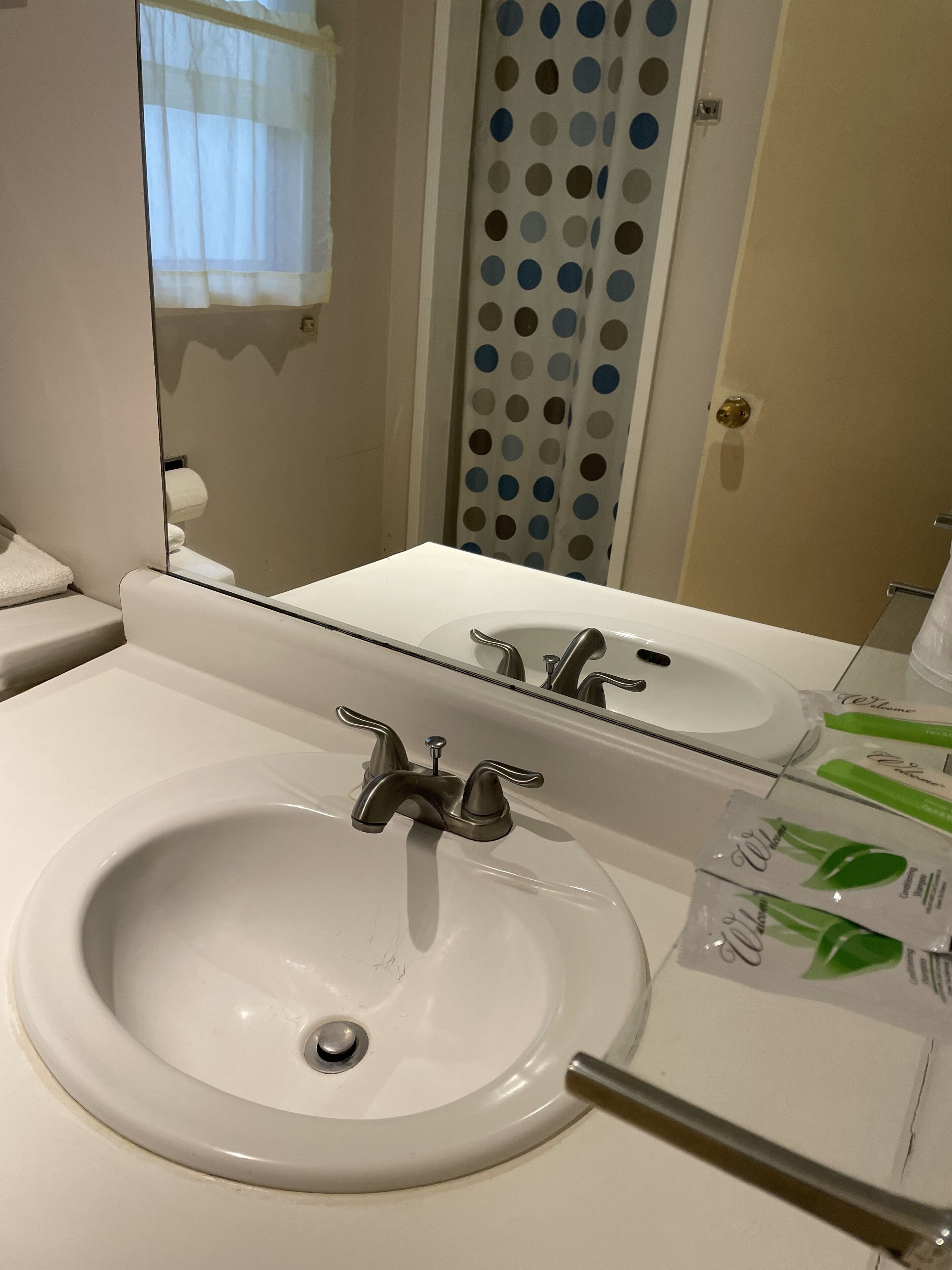 A bathroom with a white sink, a mirror, and a towel rack.