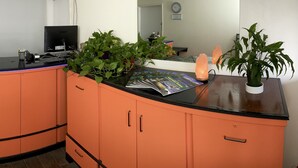 Un mostrador de recepción con un televisor de pantalla plana, un cartel que dice 'Red Bluff Inn' y diversas plantas.