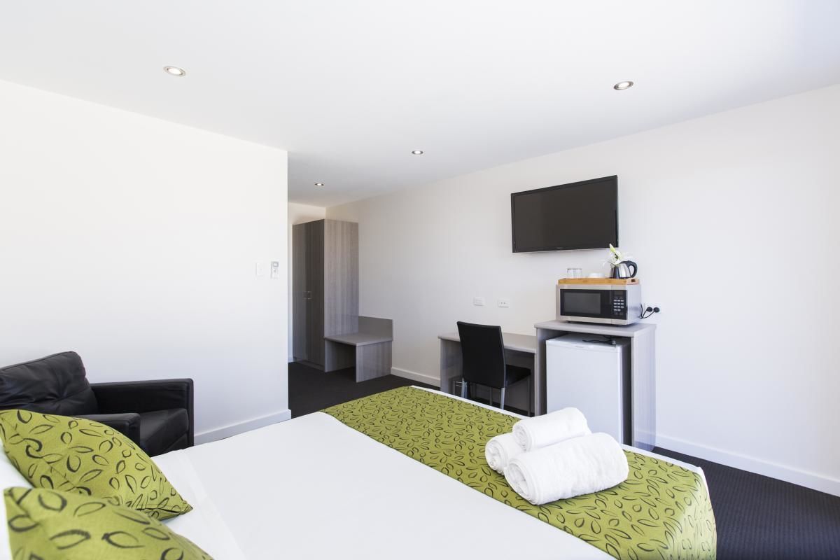 Une chambre d’hôtel équipée d’un lit, d’un bureau, d’une télévision et d’un four à micro-ondes.
