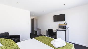Une chambre d’hôtel équipée d’un lit, d’un bureau, d’une télévision et d’un four à micro-ondes.
