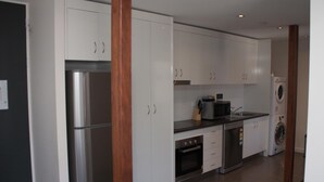A modern kitchen with white cabinets, stainless steel appliances, and a built-in oven. - Icon on Isa (Mount Isa City)