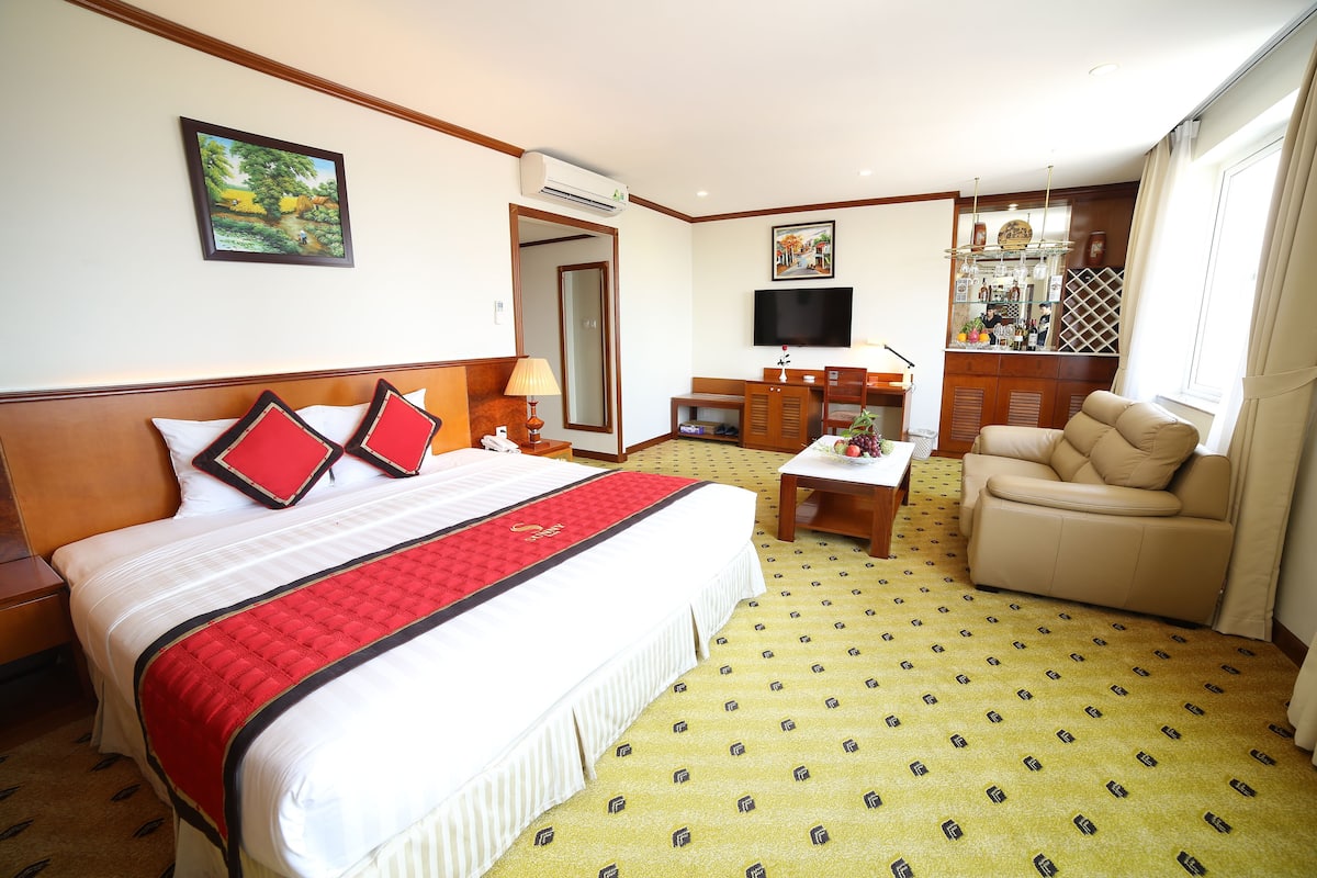 Une chambre d’hôtel équipée d’un lit, d’un bureau, d’un canapé, d’une télévision et d’un mini-bar.
