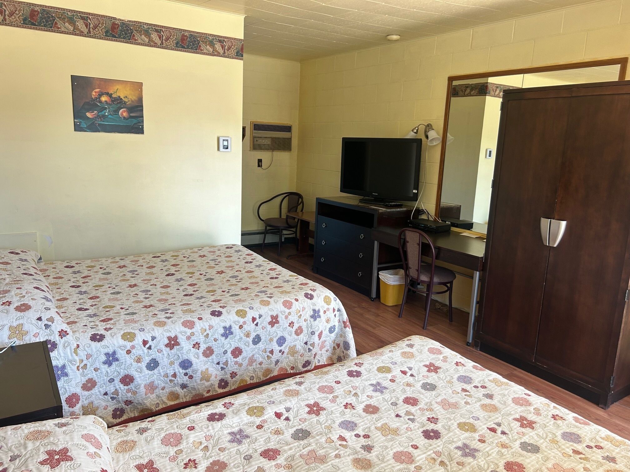 Una habitación con dos camas, un escritorio con computadora, televisión y armario.