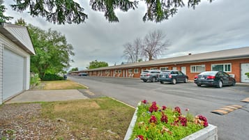 Ein Motel mit einer Reihe von Zimmern, einem Parkplatz und einem Blumenbeet im Vordergrund.