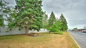 A picnic table in a grassy area with trees and a white fence. - Motel R-100 (Longueuil)