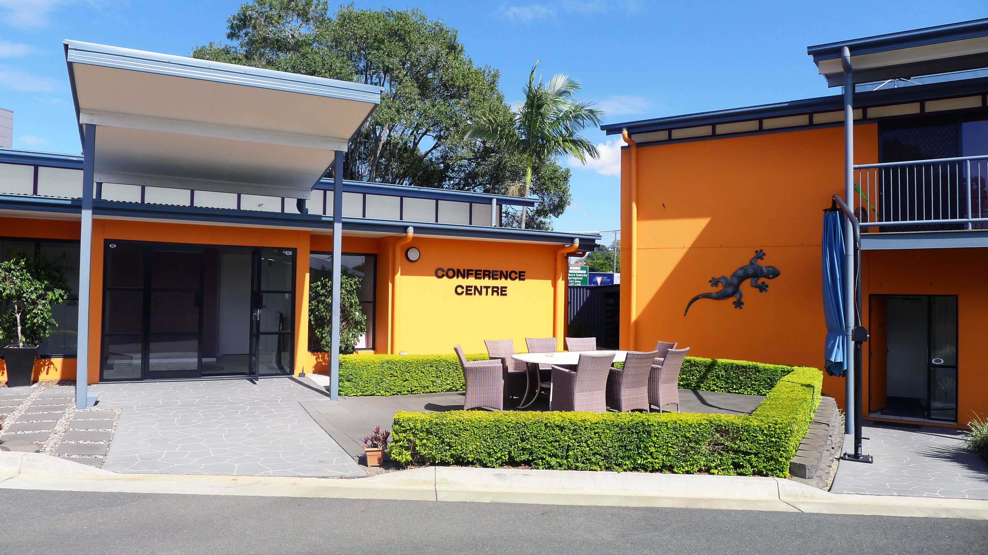 A modern building with a sign reading "CONFERENCE CENTRE" and outdoor seating.