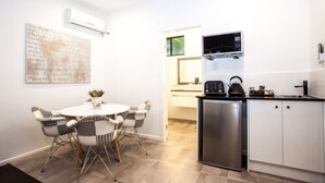 A compact kitchen with a refrigerator, a microwave, and a sink. There is a dining area with a table and chairs. - Darra Motel and Conference Centre (Darra)