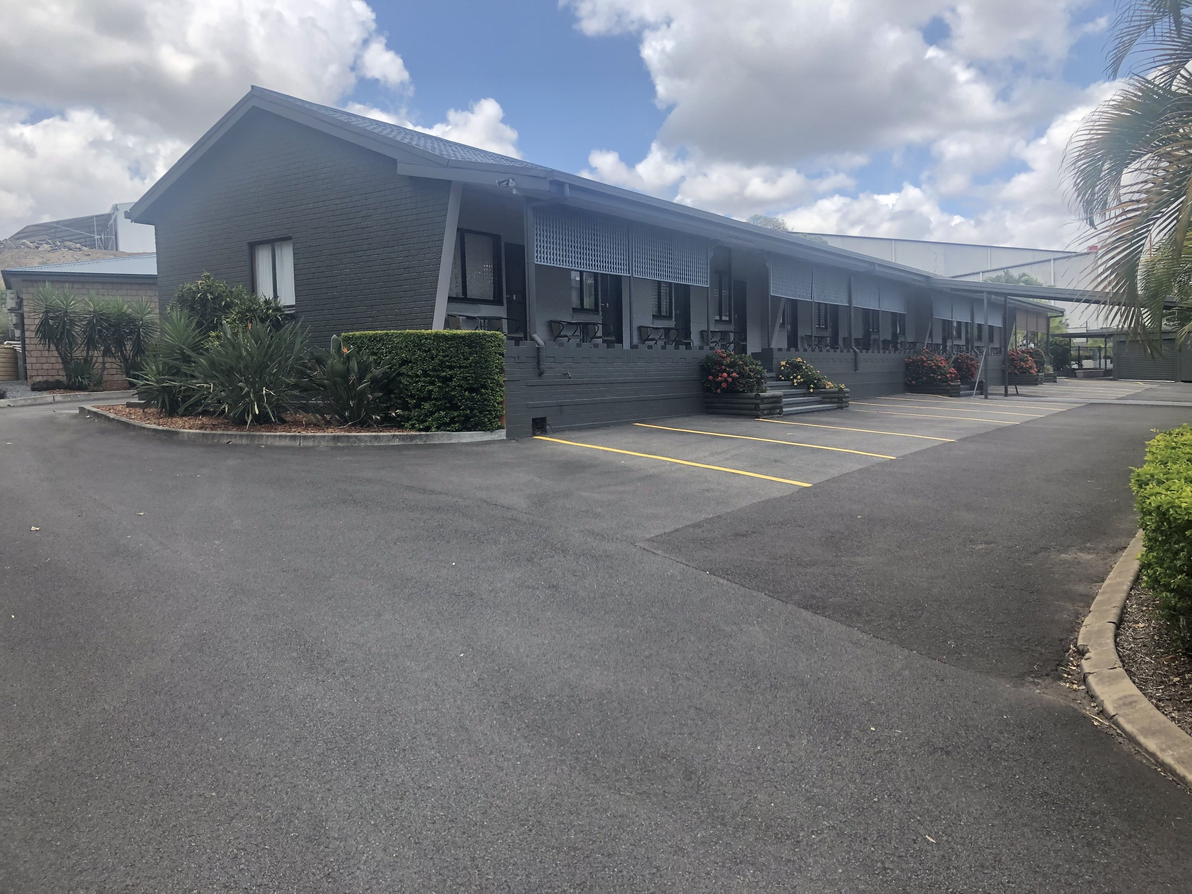 A modern building with a flat roof, large windows, and a parking lot with marked spaces.