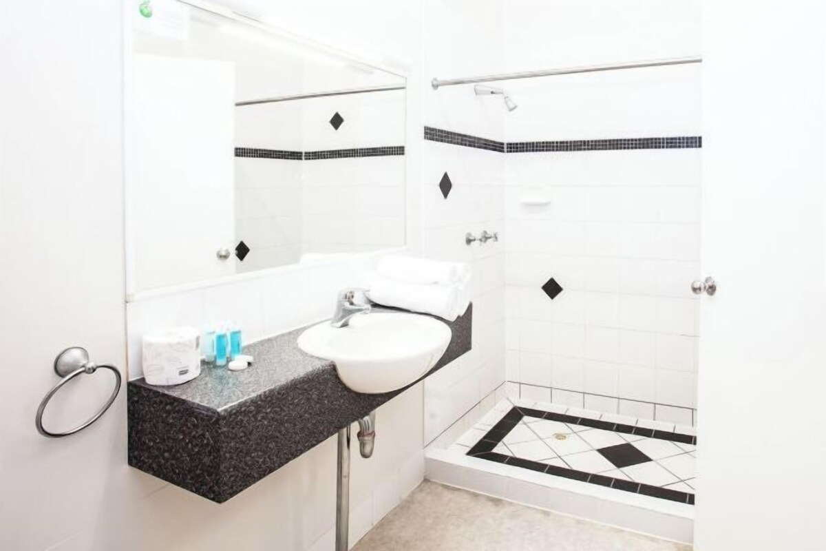 A bathroom with a sink, mirror, towel rack, and shower.