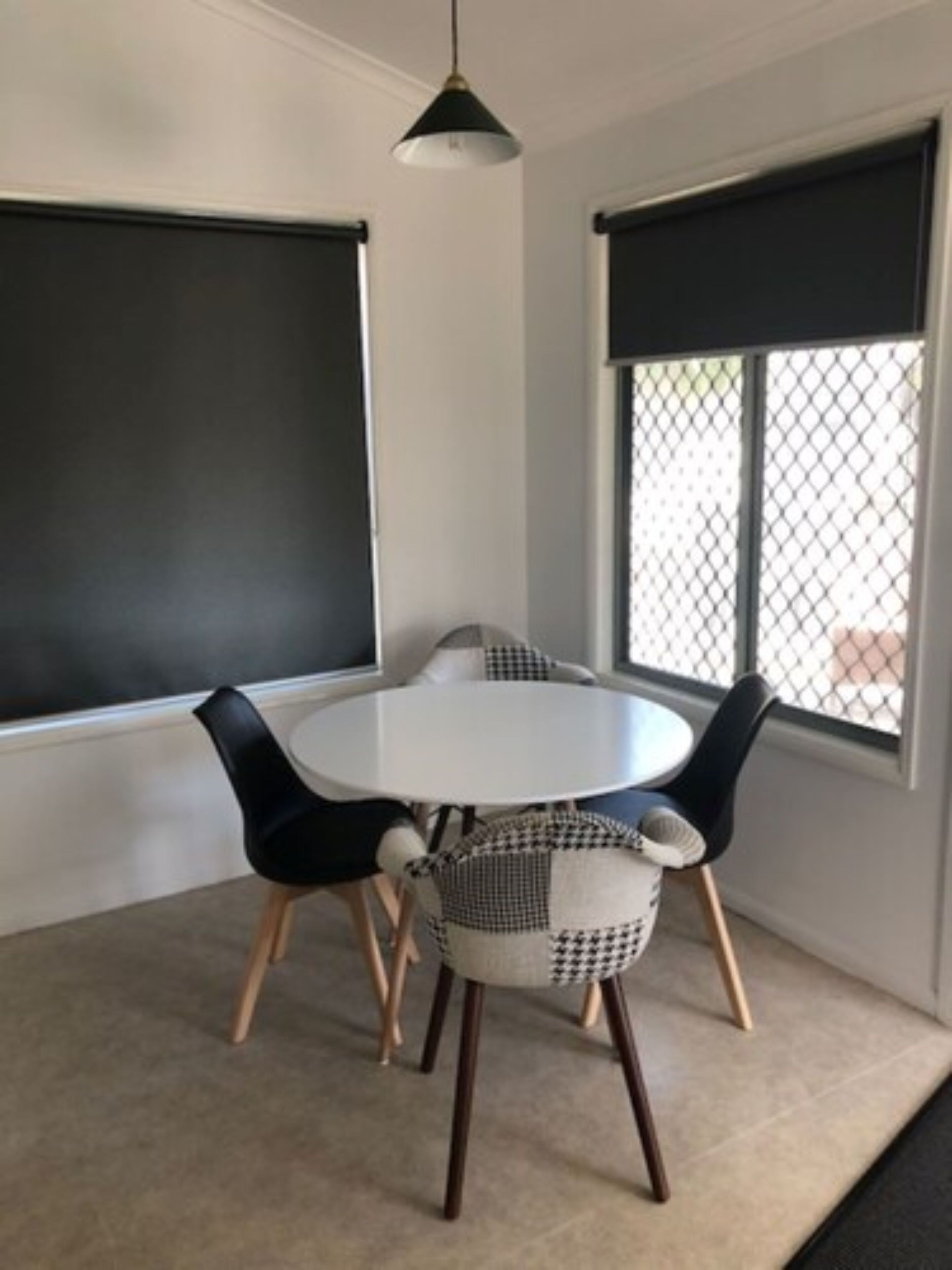 Un coin repas avec une table ronde, quatre chaises et un luminaire suspendu.