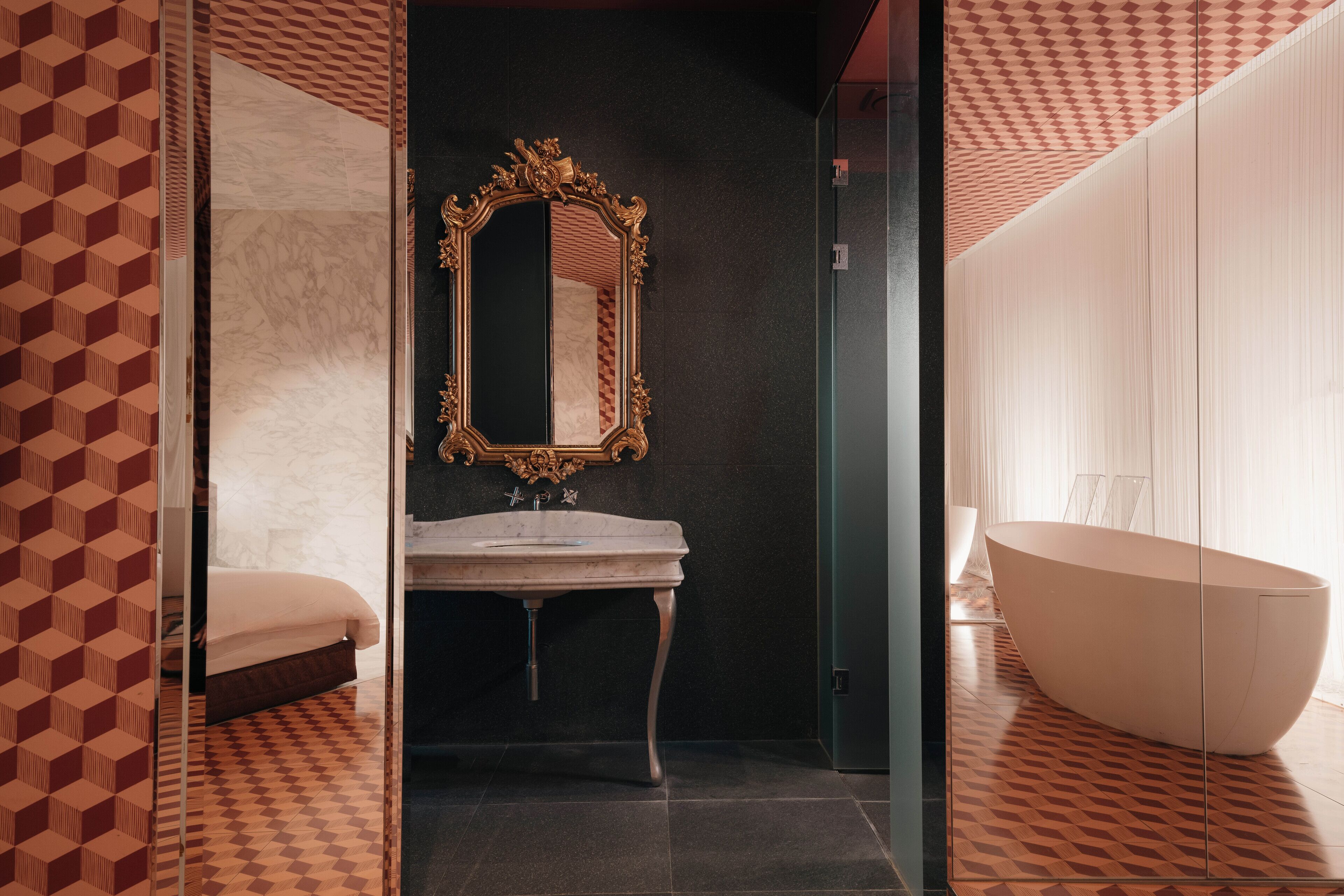 Un baño moderno con una bañera independiente, un tocador con espejo y un suelo con diseño.