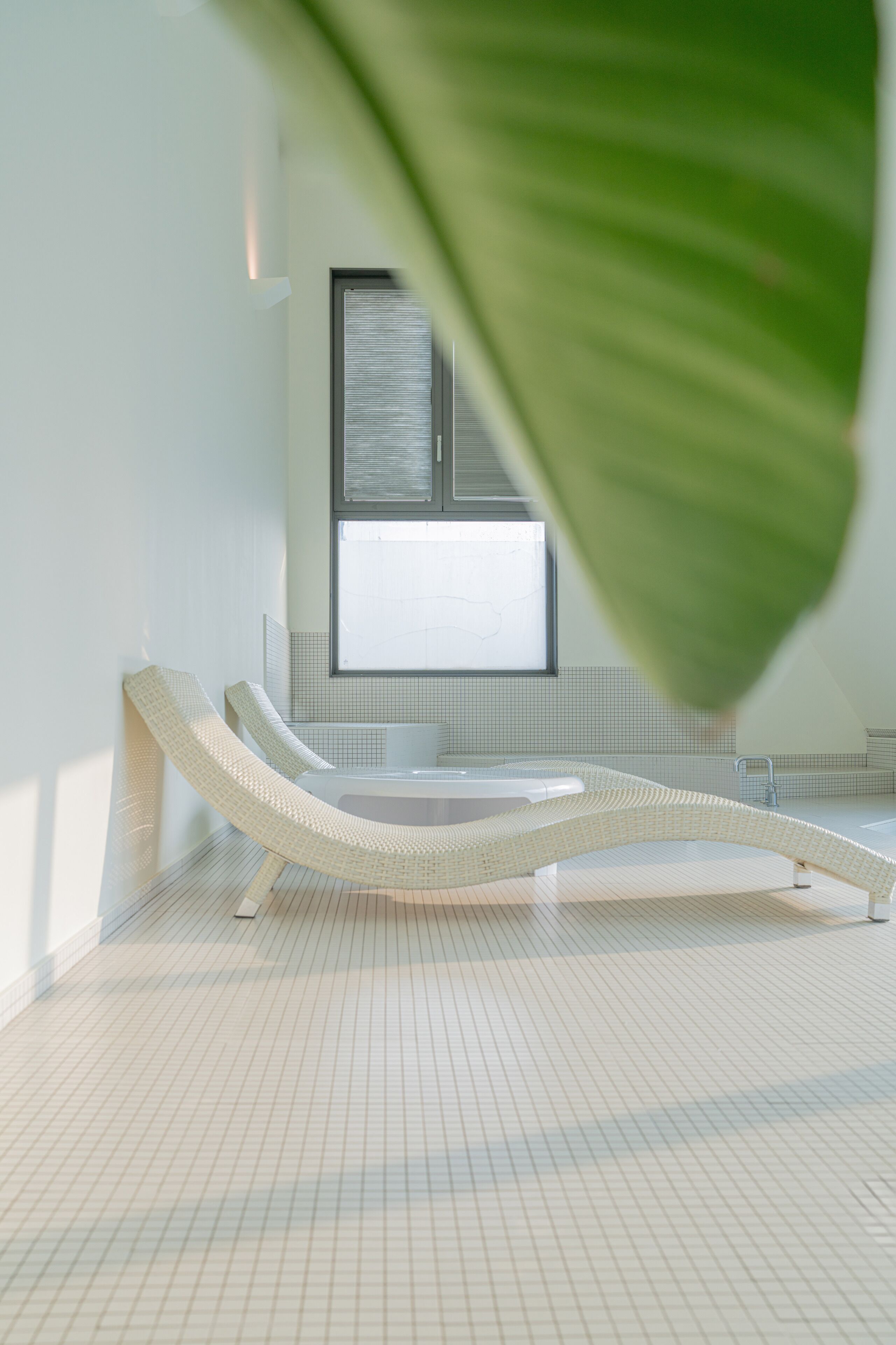 Un baño moderno con un ventanal grande, una bañera y un sillón de descanso.