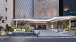 Una entrada de hotel moderna con fachada de vidrio, pared de ladrillo y un letrero que dice "HOTEL".
