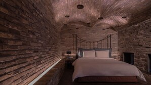 Un dormitorio con pared de ladrillo, una cama y una lámpara colgante.