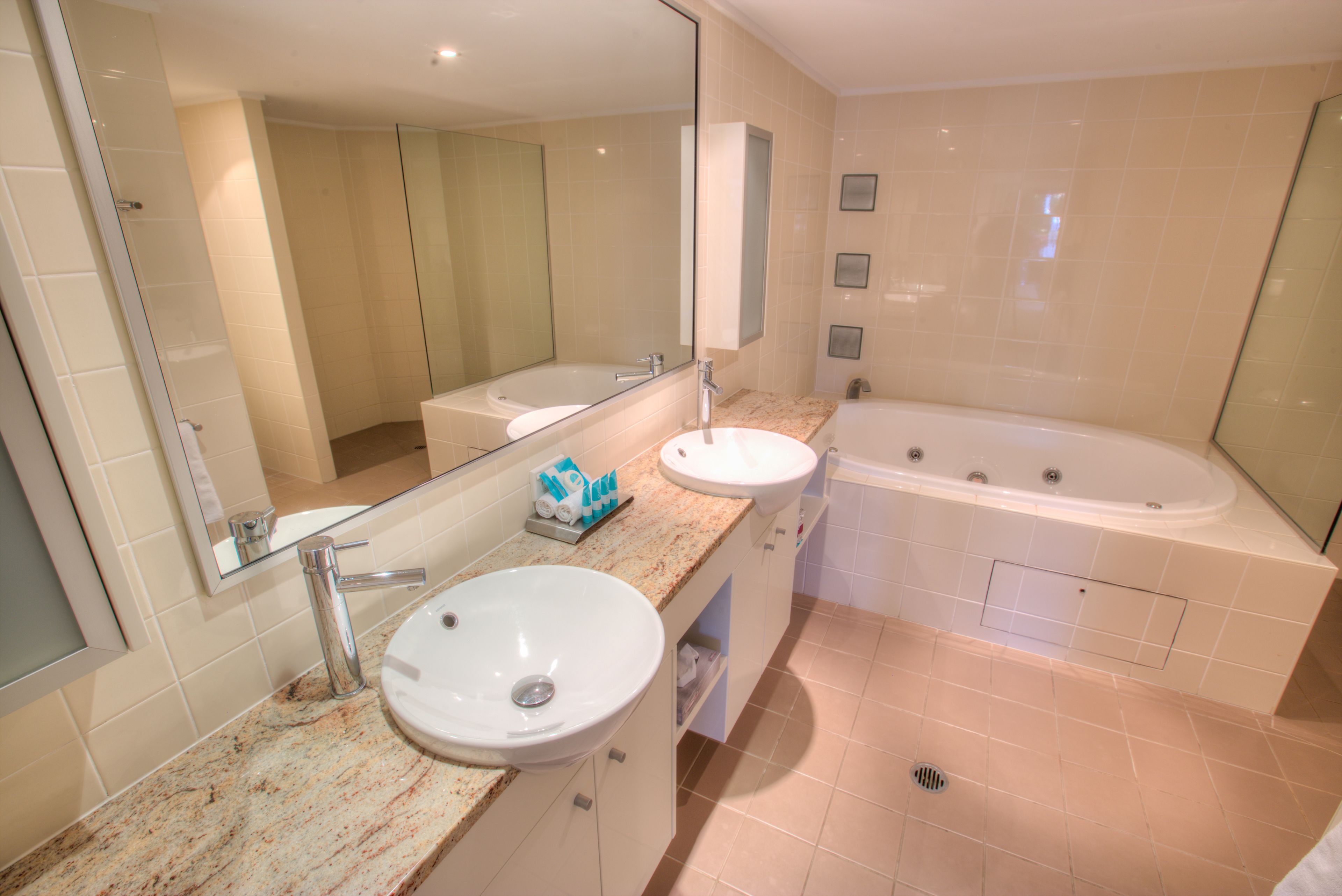 Un baño moderno con un espejo grande, un lavabo, una bañera y un mueble tocador con encimera.