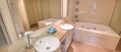 Un baño moderno con un espejo grande, un lavabo, una bañera y un mueble tocador con encimera.
