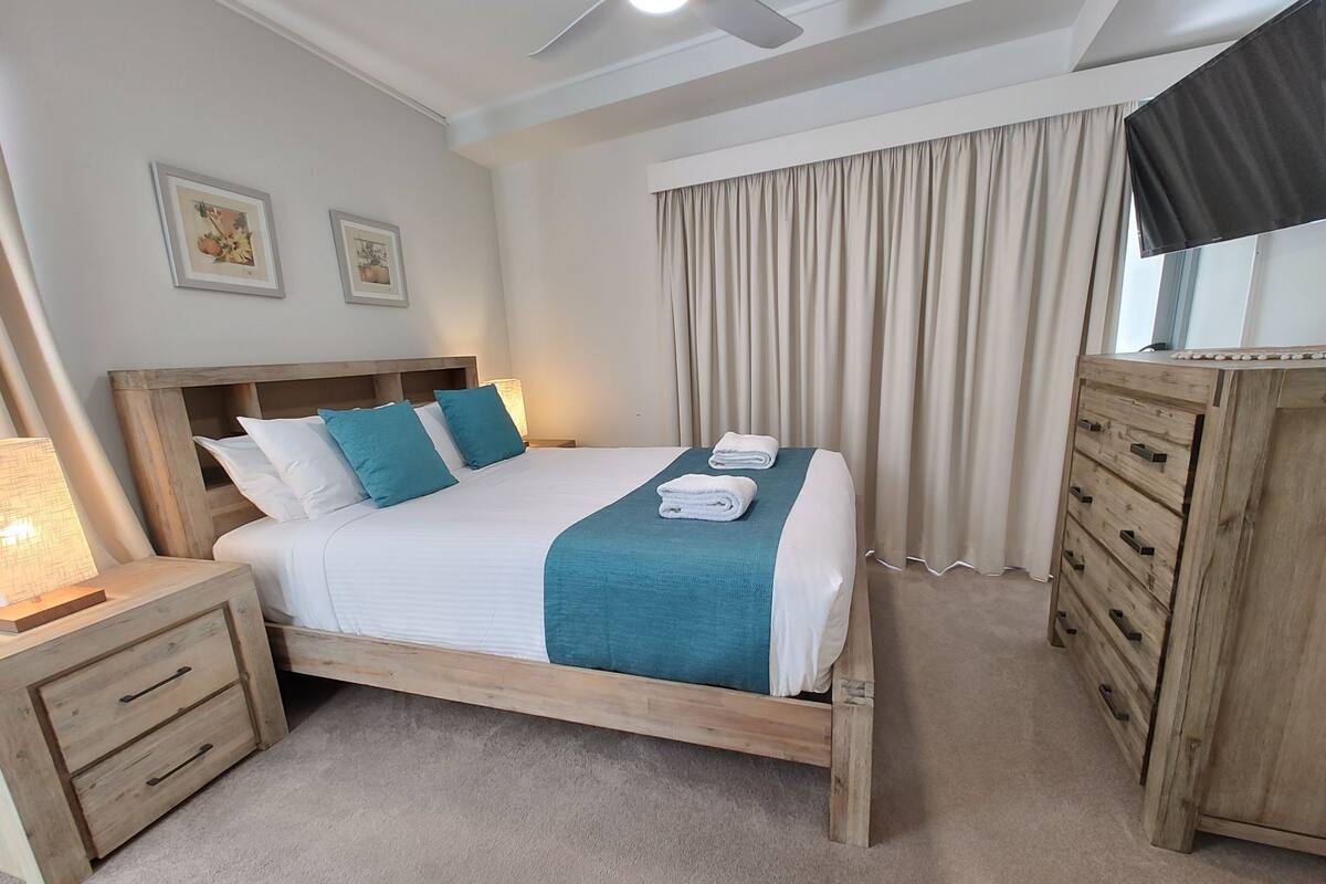 A neatly arranged bedroom with a bed, bedside tables, a dresser, and a ceiling fan.