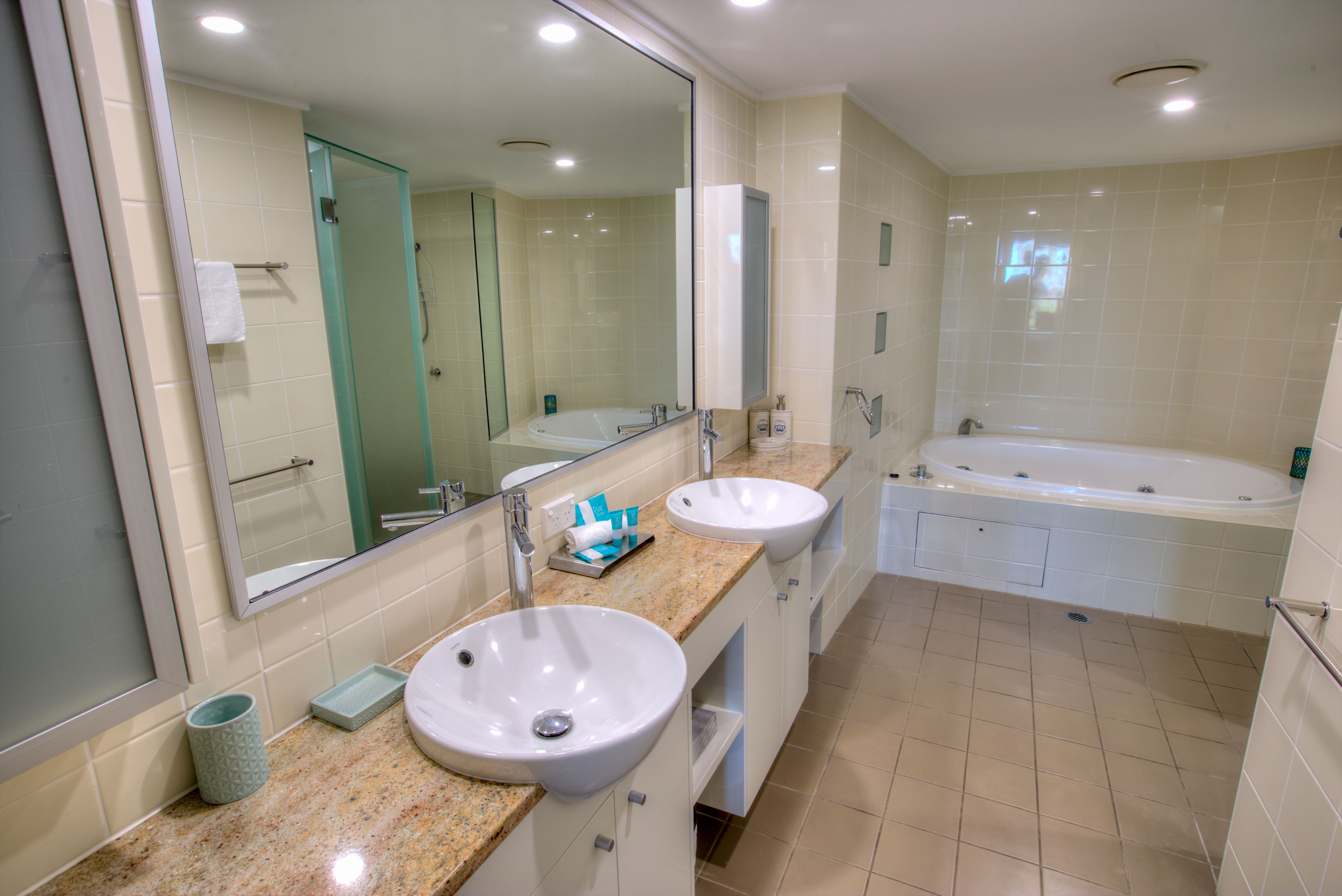 Une salle de bain moderne avec deux lavabos, un grand miroir et une baignoire.