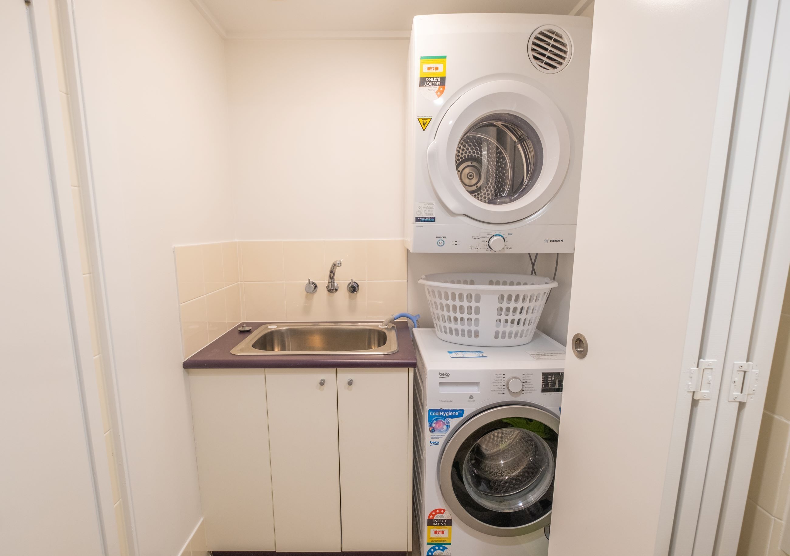 A compact laundry room with a washing machine, a dryer, and a sink.