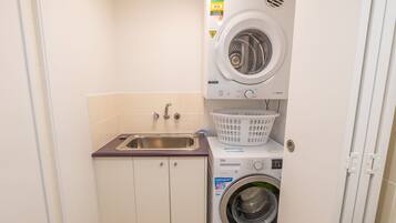 A compact laundry room with a washing machine, a dryer, and a sink.