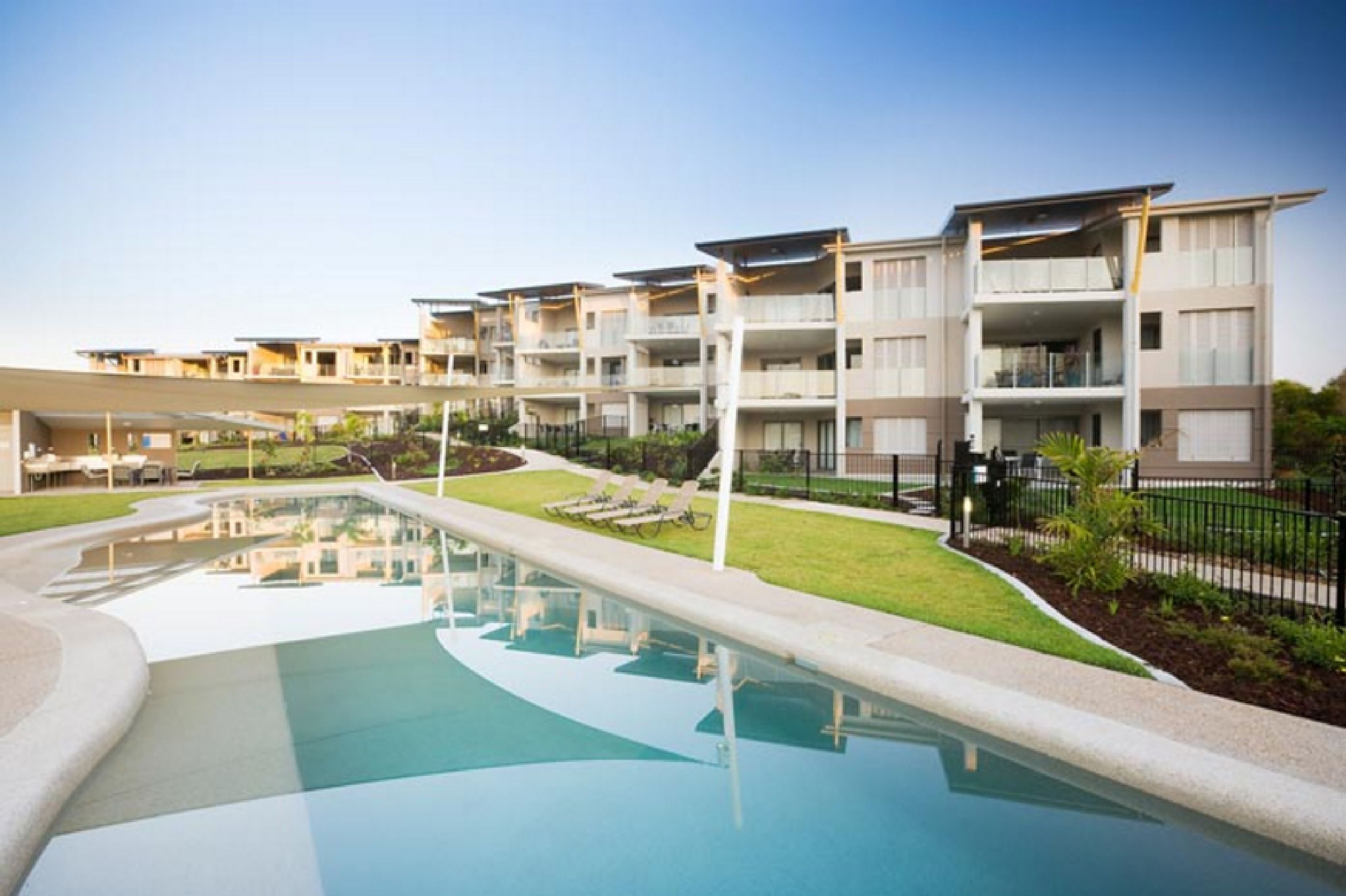 Un hôtel moderne doté d’une piscine, de nombreux balcons et d’un espace pelouse bien entretenu.