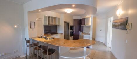 Una cocina moderna con una isla curva, taburetes de bar y electrodomésticos integrados.