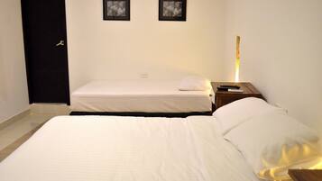 Una habitación de hotel con dos camas, una mesita de noche con lámpara y dos cuadros en la pared.