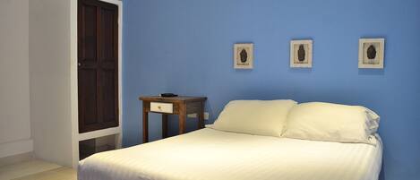 Un dormitorio con cama, mesita de noche, cómoda y dos cuadros en la pared.