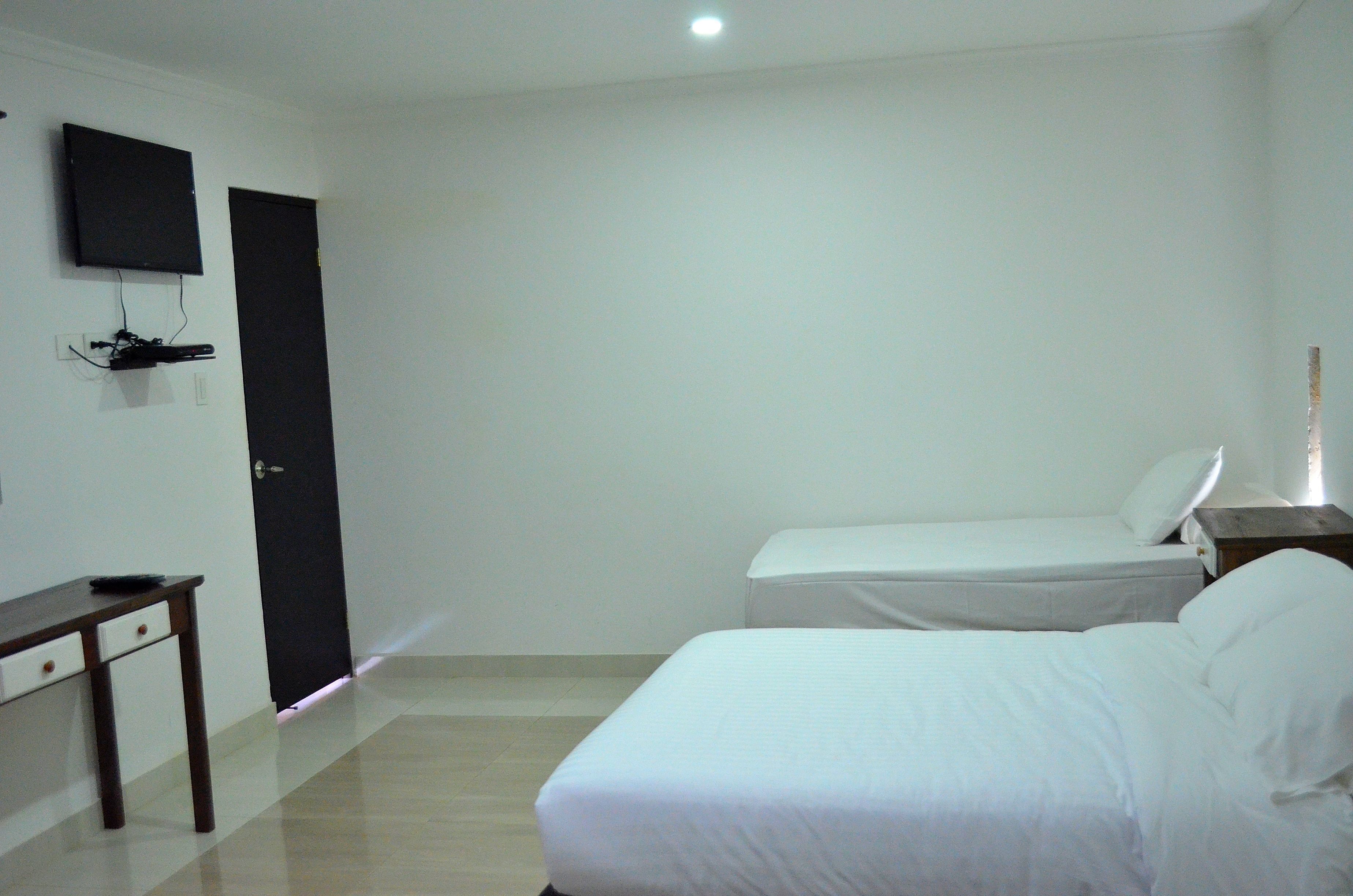 Una camera da letto con un letto, un comodino, una TV a parete e una porta.