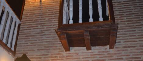 A brick wall with two wooden benches and two wall-mounted lanterns.