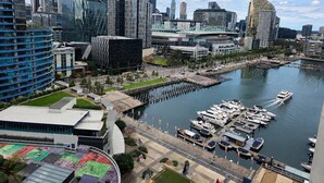 A cityscape with modern buildings, a marina with boats, and a waterfront promenade. - Harbour Escape Apartments (Docklands)